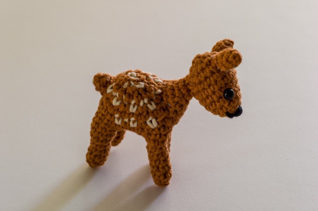 Photo of the light brown deer taken from a higher angle, showing the white spots across its back.